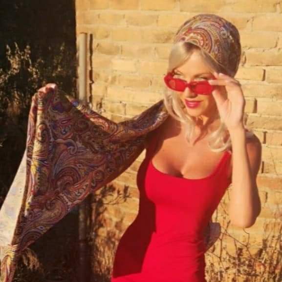 Red dress with a paisley scarf against a brick wall