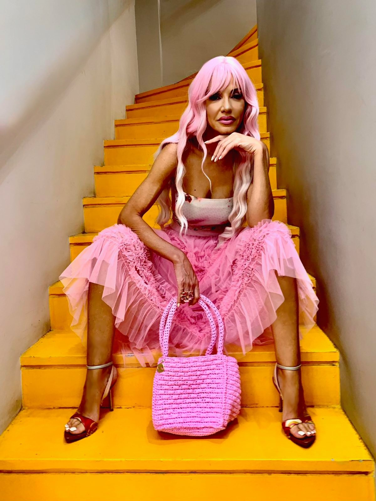 Pink tulle skirt with handmade crochet bag on yellow stairs