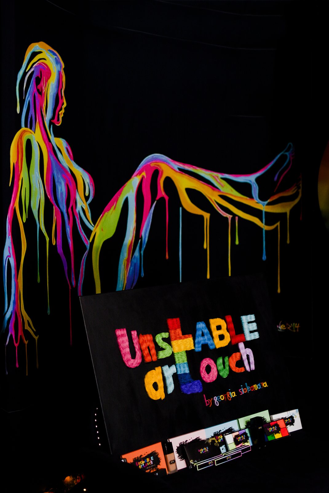 Dripping neon muse painting behind the Unstable Art Touch sign