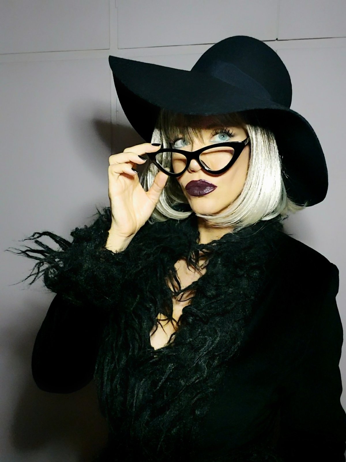 Black felt hat, platinum bob and shaggy black coat