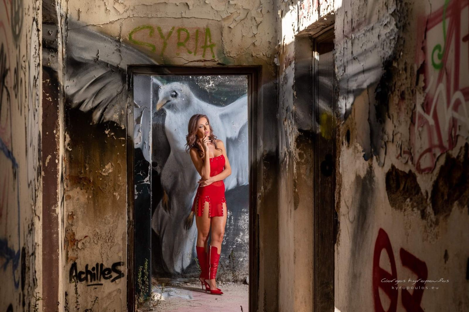 Red mini dress framed by a dove mural in an abandoned building